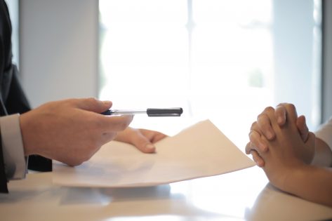 Hands Holding Pen and Insurance Papers