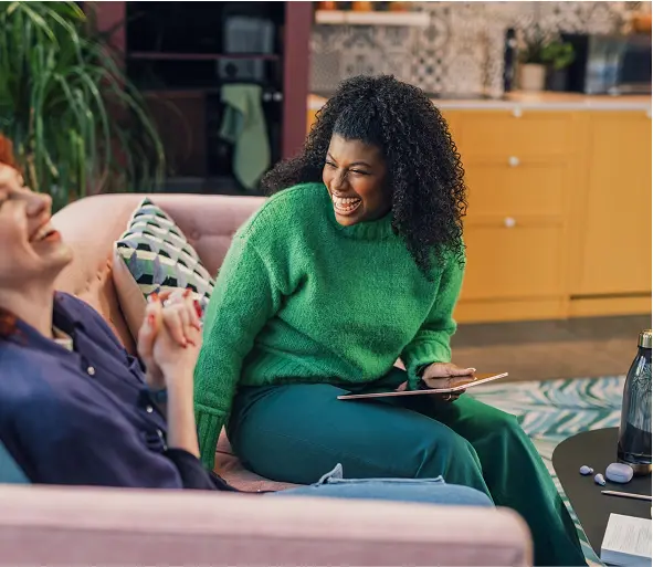 A woman and a child are sitting together on a bench indoors, both looking comfortable.